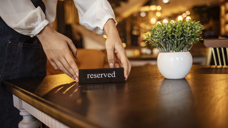 Waitress reserving a tablet at a restaurant and putting a sign on the table