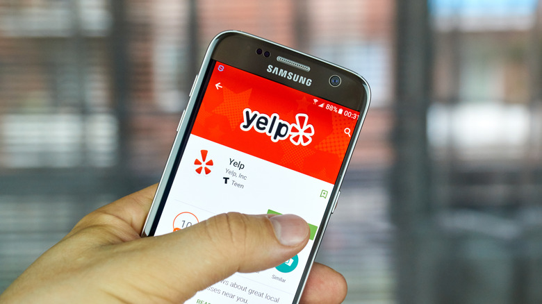 Hand holding phone with the Yelp app