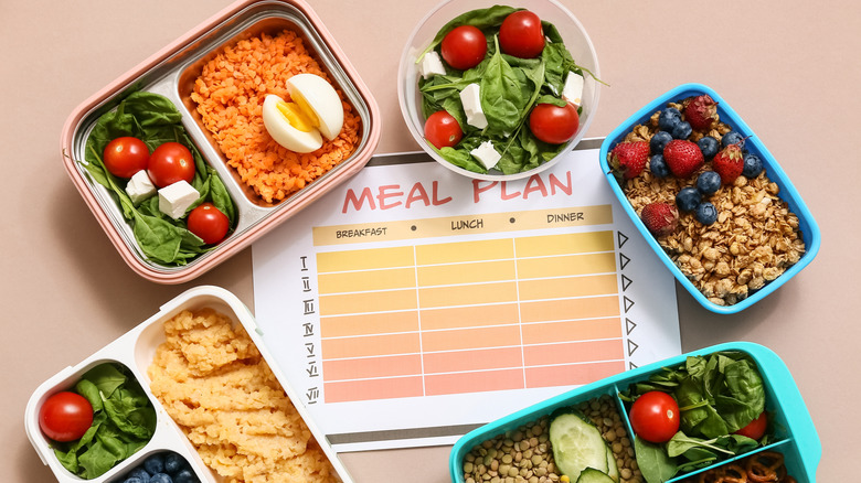 Healthy products and weekly meal plan on brown background.