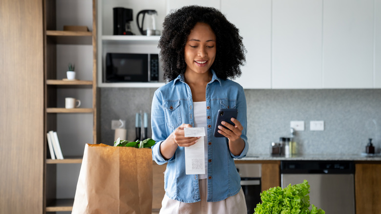 Woman at home checking the receipt after ordering groceries using a mobile app