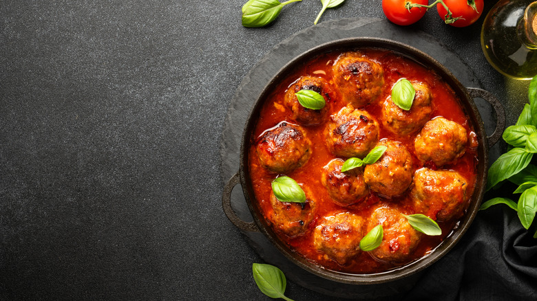 Meatballs in a cast iron pot garnished with fresh basil