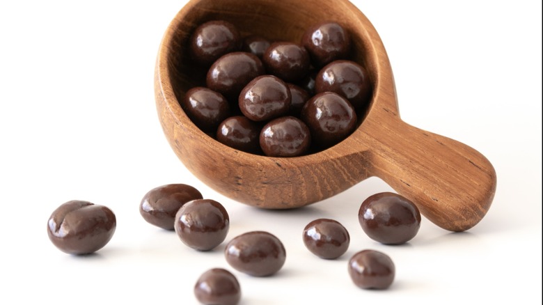 Chocolate Covered Coffee Beans Spilled from a Wood Scoop