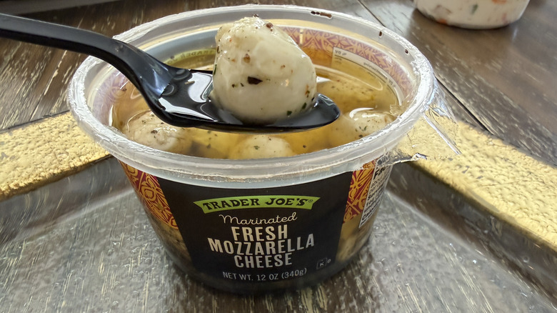 Tub of Trader Joe's Marinated Fresh Mozzarella on gold rimmed plate with a spoon