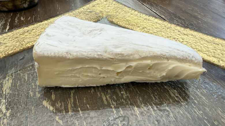 Wedge of Trader Joe's Triple Creme Brie cheese on gold rimmed plate