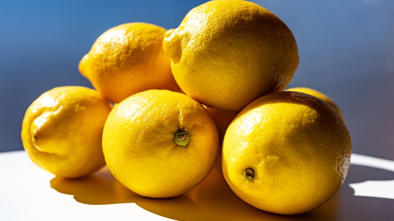 Stack of ripe yellow lemons on a bright surface with soft natural light.