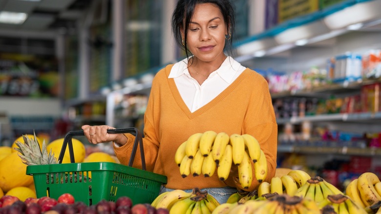 Woman evaluates quality of a bunch of bananas in the grocery store