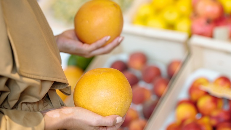 Hands holding fresh ripe yellow grapefruits while choosing which one to take