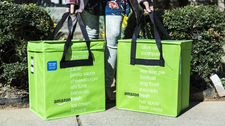 Amazon Fresh insulated grocery delivery bags on front porch closeup with someone picking them up