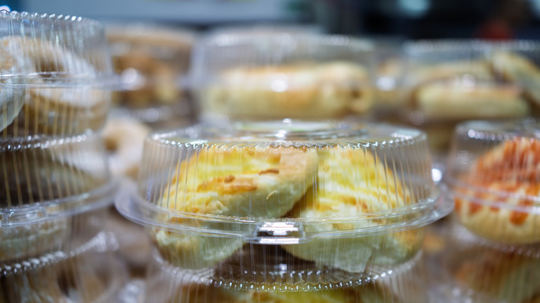 A close-up, front-view shot of stacks of clear plastic clamshell containers filled with baked goods