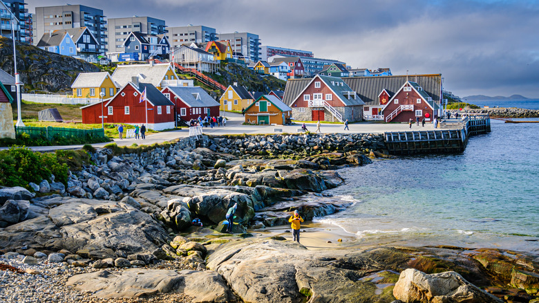 Two people walk on a rocky beach in Greenland