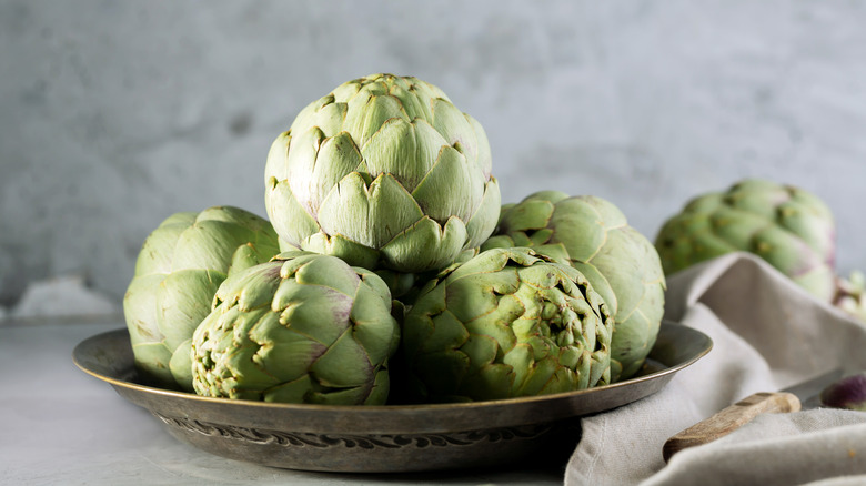 A bowl of whole uncooked artichokes