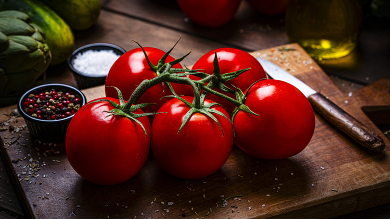 A bunch of tomatoes on a cutting board