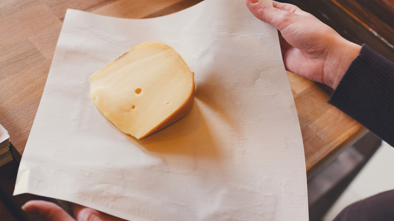 Person wrapping cheese in wax paper