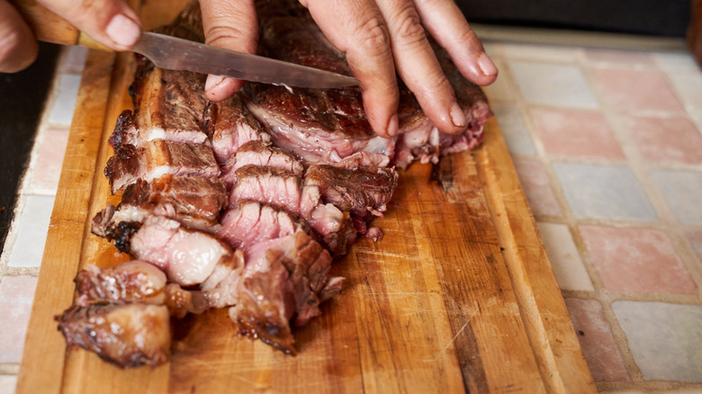 Person slicing beef on cutting board