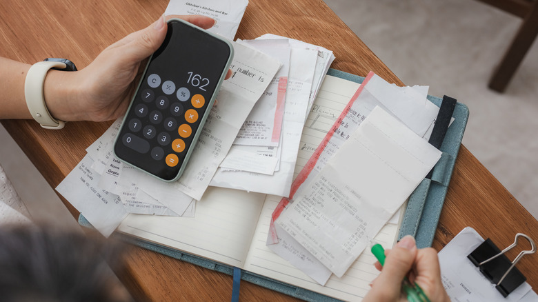 Creating a budget with a pile of receipts, a journal, and a smartphone.