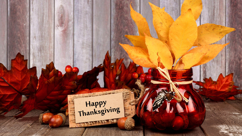 Fall foliage in a red glass jar with a Happy Thanksgiving tag.