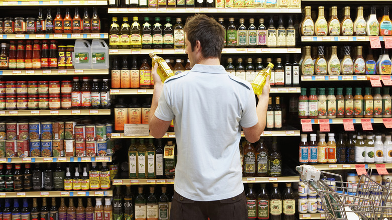 Many comparing labels in front of a grocery store shelf.