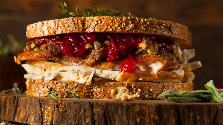 Sandwich made from Thanksgiving leftovers with cranberry salad, stuffing, and turkey.