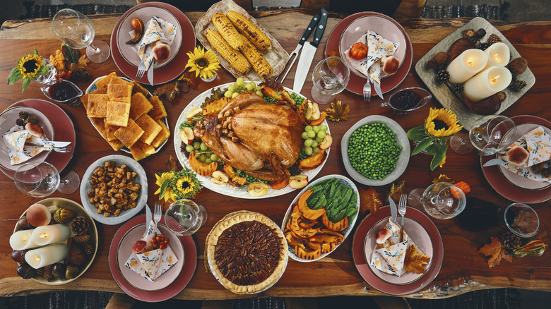 Overhead view of Thanksgiving spread with a turkey surrounded by pies and sides on a wooden table.
