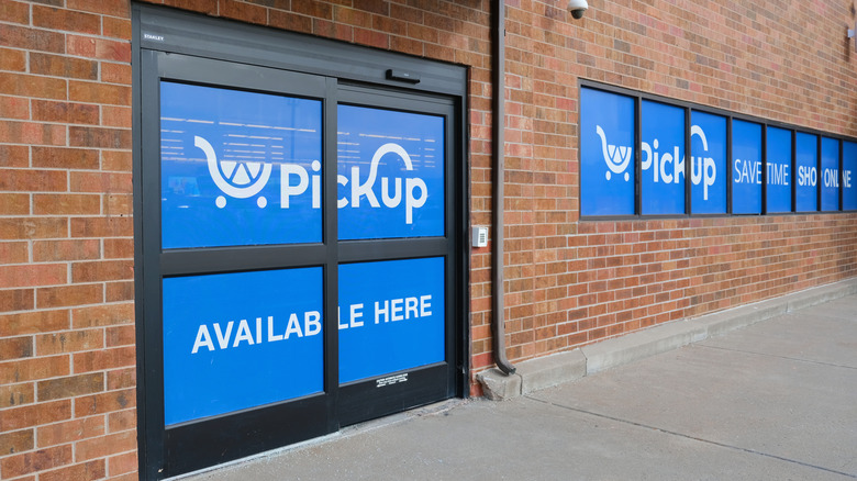 Blue curbside pick up sign on a brick grocery store.