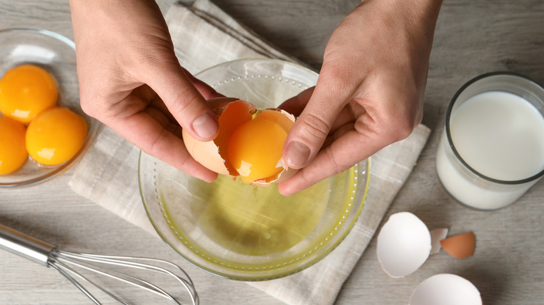 Woman's hands separating eggs in bowl