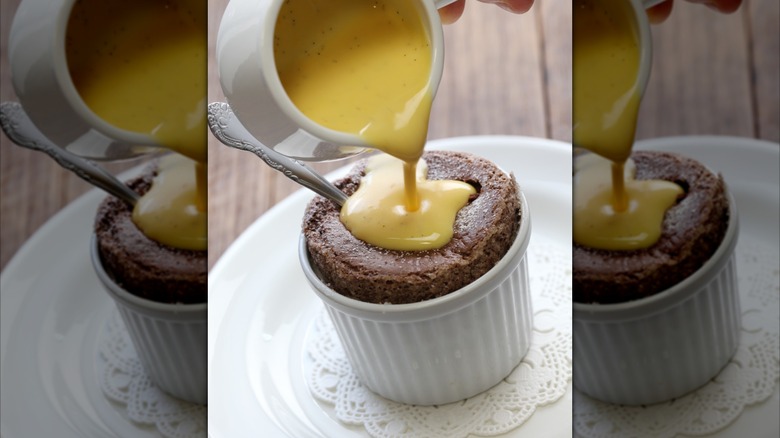 Creme anglaise being poured from a jug onto a chocolate souffle