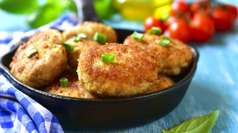 Chicken cutlets in a skillet on a blue wooden surface