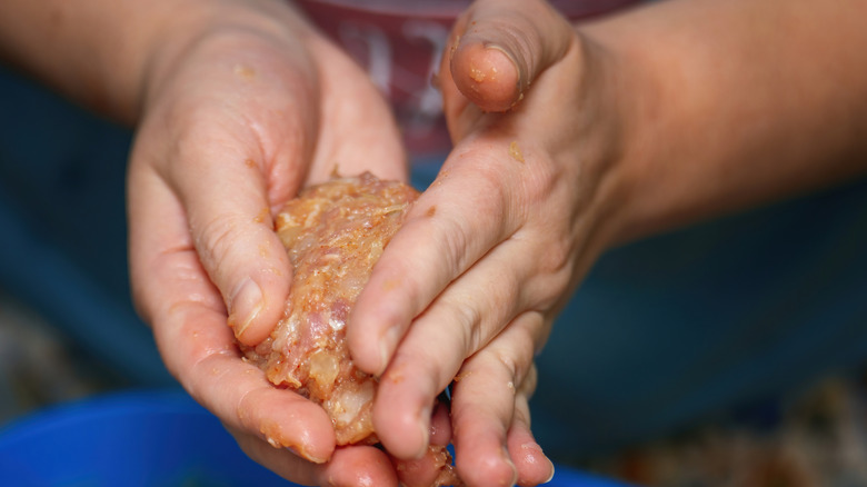 Hands shaping ground meat with onion into a patty