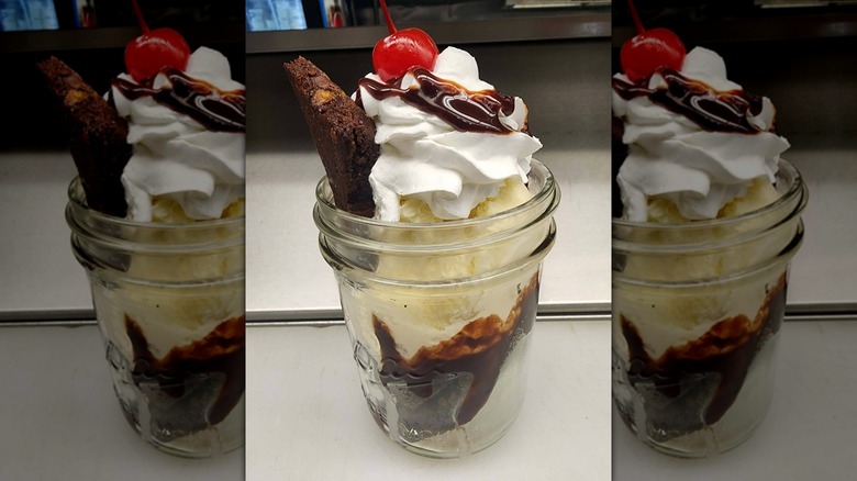 Ice cream in a mason jar with whipped cream and cherry