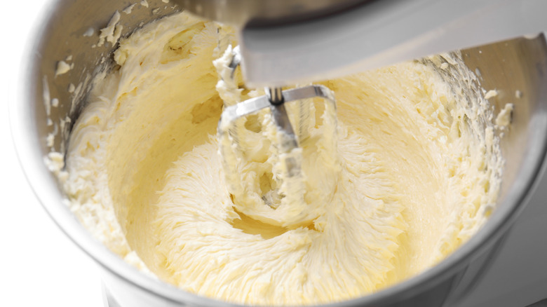 Whipping cream in mixing bowl with hand mixer running