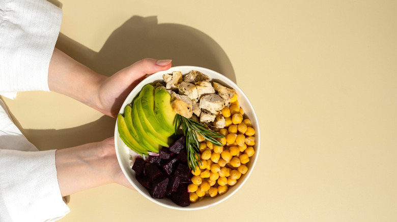 A grain bowl with various proteins and vegetables, including avocado, chickpeas, beets, and chicken