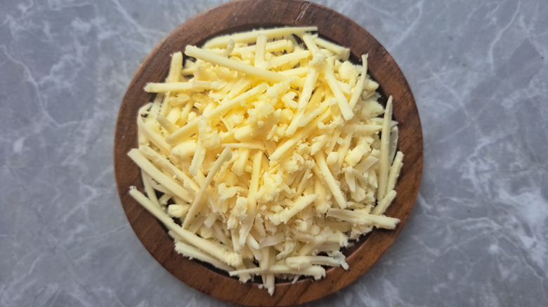 A small wooden bowl of shredded cheese