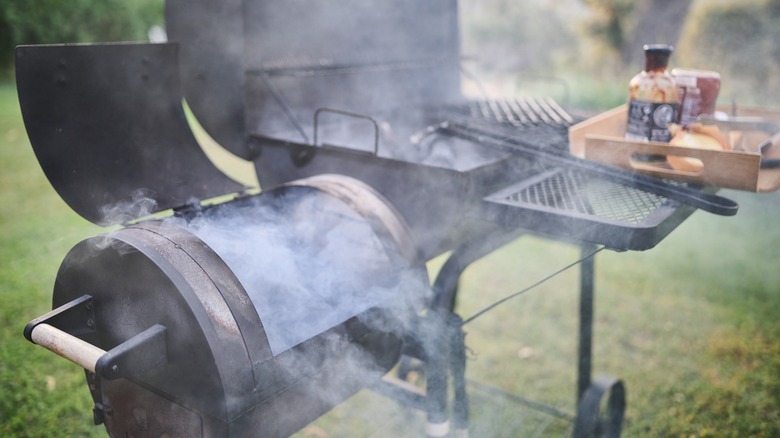 Barbecue with smoker box releases smoke from burning charcoal.
