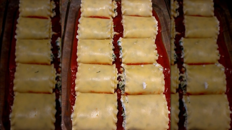 Lasagna roll-up on a white plate next to a glass of red wine.