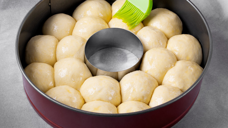 Raw balls of dough in a round baking dish.