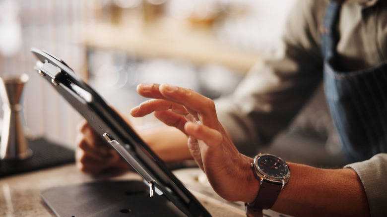 A bartender enters an order for payment on a touch screen pos system.