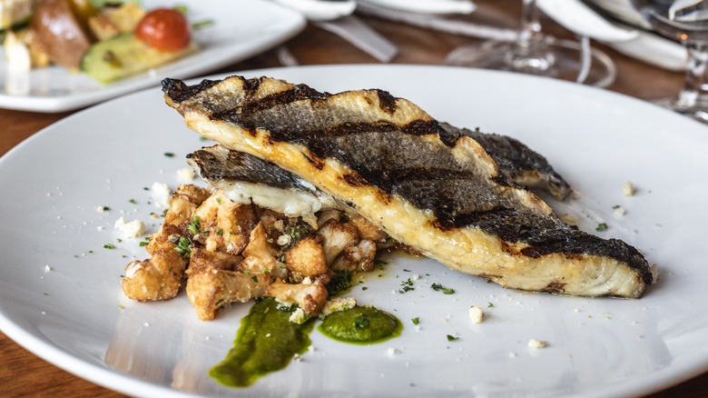 Seared branzino on a white plate in restaurant