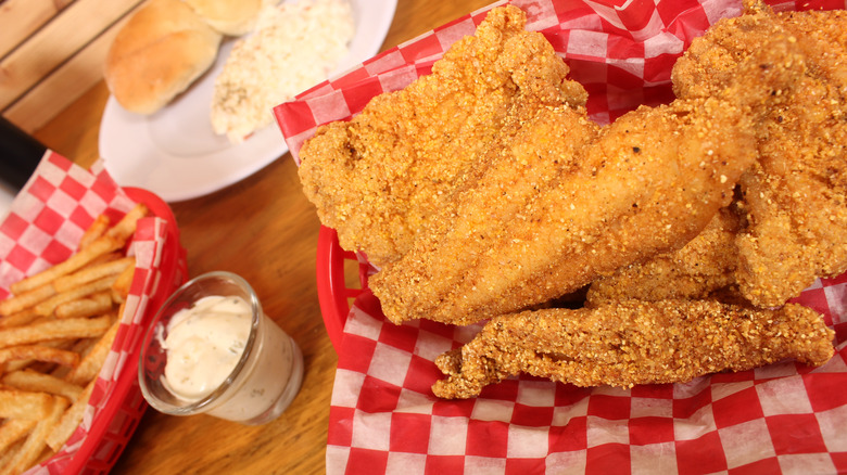 Fried catfish in red and white checkered basket, with coleslaw and french fries