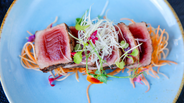 Close up of tuna tataki with salad on blue plate