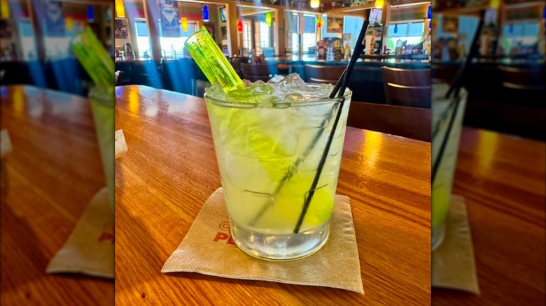 A small margarita on a wooden table with an empty restaurant in the background
