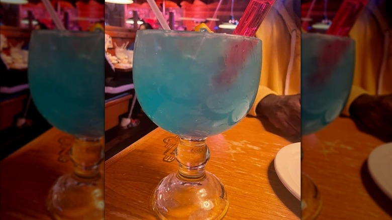 A light blue liquid in a goblet style glass