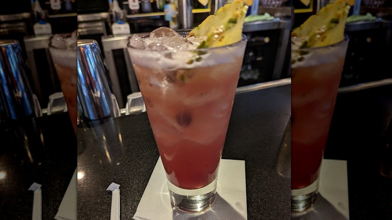 A light pink cocktail in a tall glass on a bar top