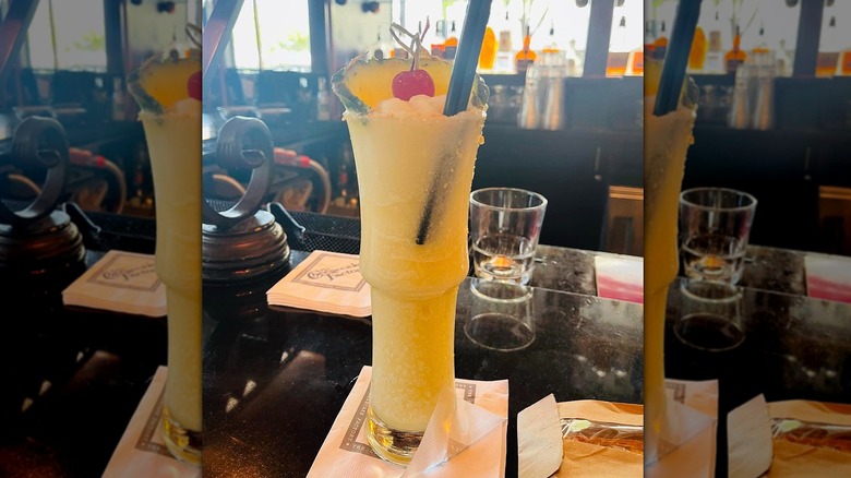 A frozen Piña Colada in a curved glass garnished with pineapple and cherry