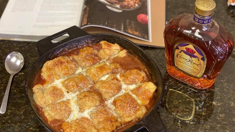 Peach pandowdy in an iron pan next to maple syrup