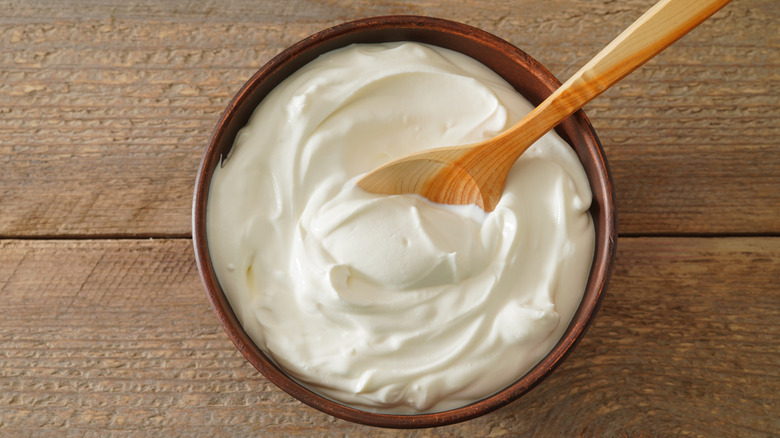 Sour cream in a wood bowl with a wooden spoon