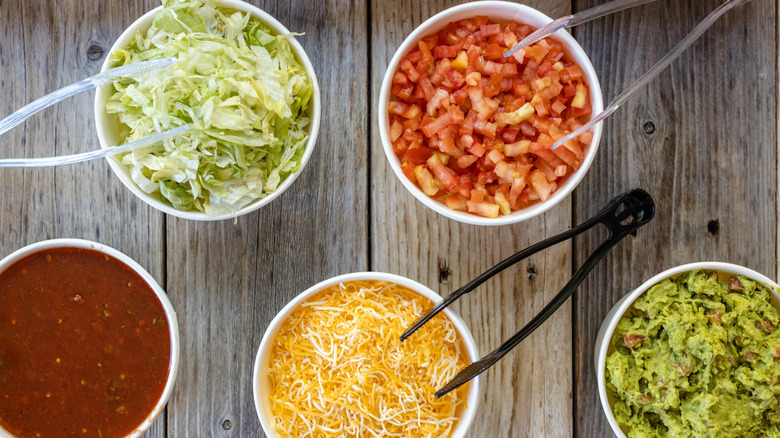Bowls of taco ingredients on a wooden table