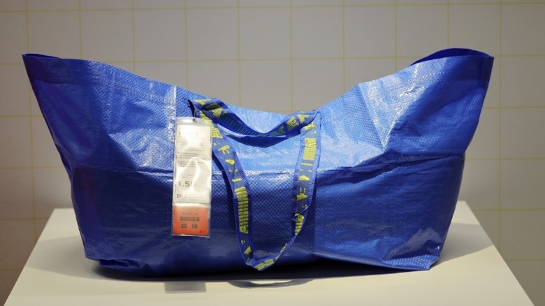 large blue IKEA bag on a white table with tiled background wall