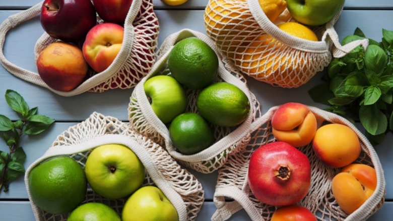 apples, peaches, limes, and pomegranates in white mesh produce bags