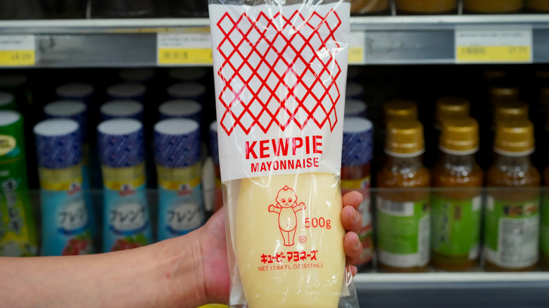 Close up of Japanese style Kewpie brand mayonnaise held in hand in a local supermarket aisle