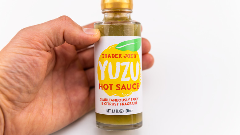 Yuzu hot sauce of Trader Joe's made in Japan isolated on white background with hand holding product